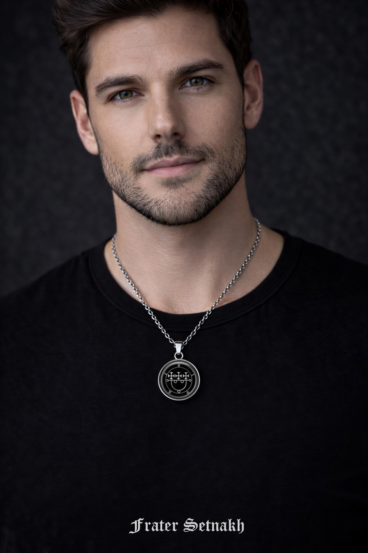 A man wearing a black shirt and a silver necklace with a pendant, looking directly at the camera.
